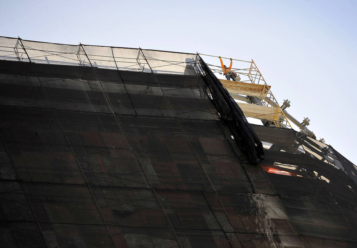 A worker installs scaffolding along the top edge of the Harmon Hotel as the demolition of the u ...