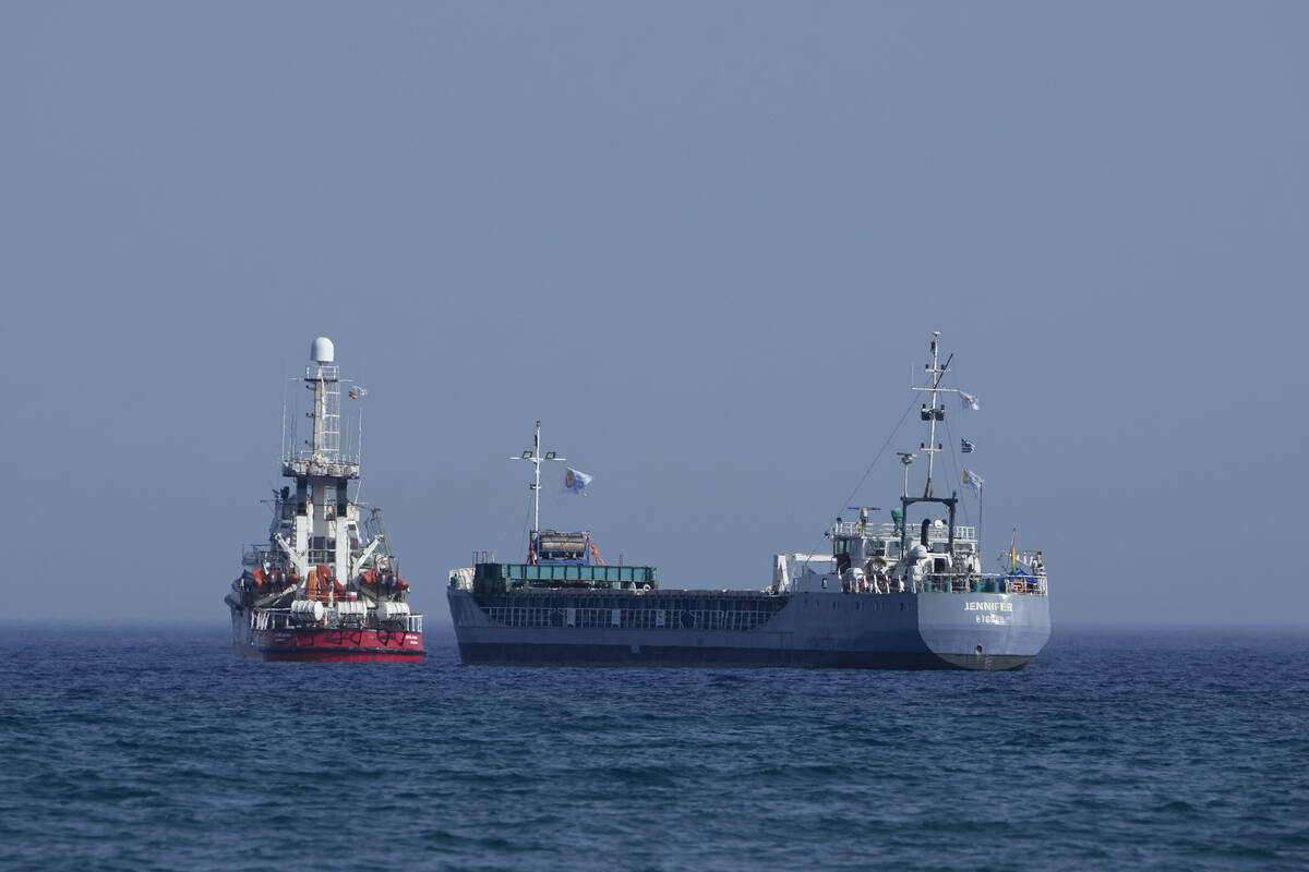 A cargo ship, right, and a ship belonging to the Open Arms aid group, are loaded with 240 tons ...