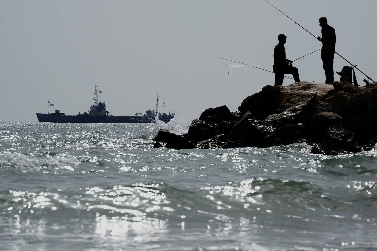 Men fish as in the background is seen a ship loaded with 240 tons of canned food destined for G ...