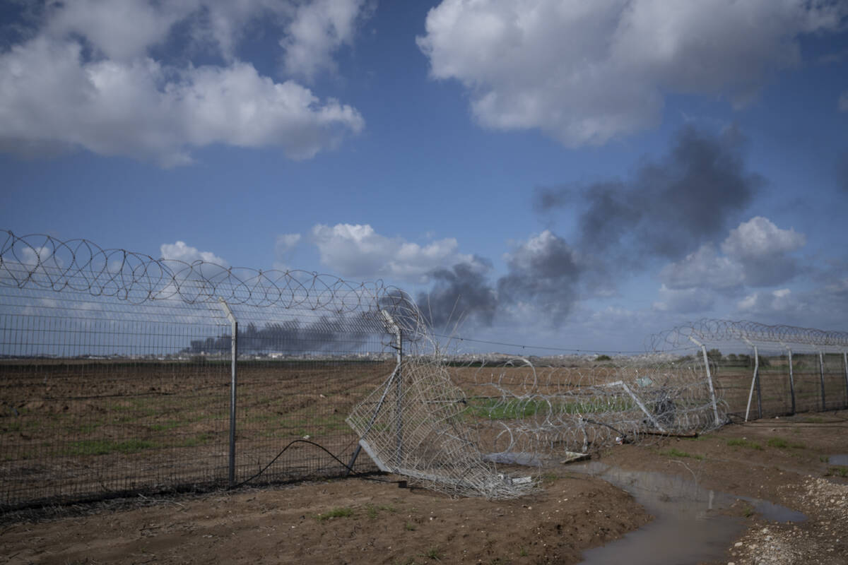 Smoke rises from the north of the Gaza Strip on Jan. 30, 2024, seen behind a gap in the fence o ...