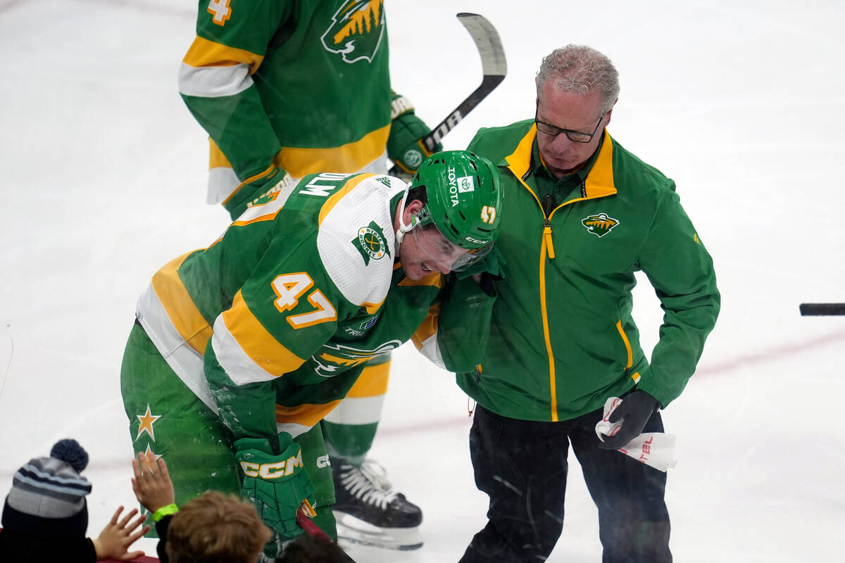 Minnesota Wild defenseman Declan Chisholm (47) is attended to by a trainer after sustaining an ...