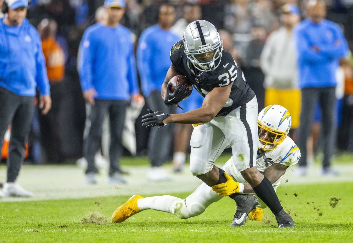 Raiders running back Zamir White (35) looks to break a tackle attempt by Los Angeles Chargers c ...