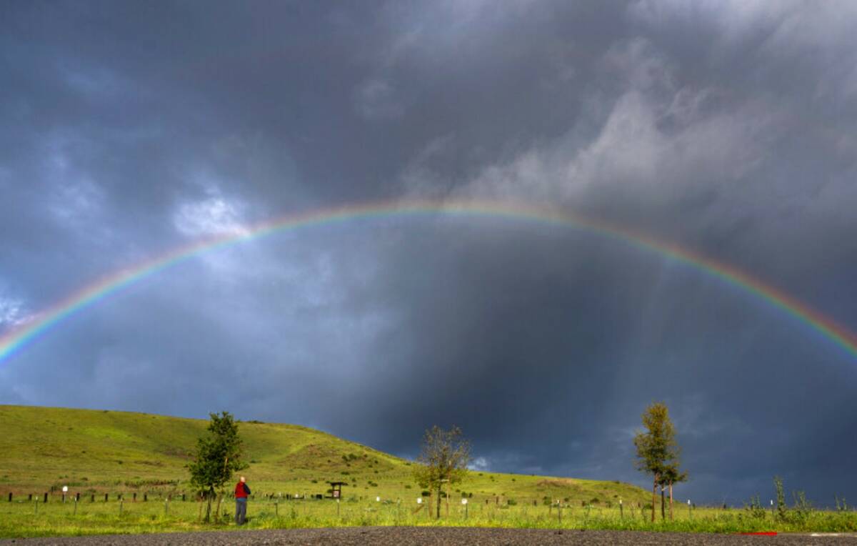 Adwait Bhagwat, of Irvine, stops to photograph a full rainbow seen over a meadow near the Inter ...
