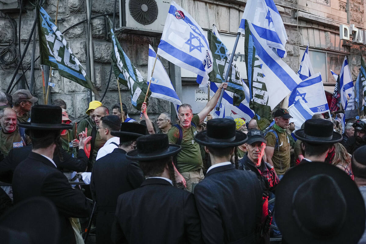 Members of the 'Brothers in Arms' reservist protest group wave Israeli flags during a demonstra ...