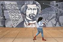 A woman walks past a mural in tribute to Frederick Douglass on the exterior wall of the Black-o ...