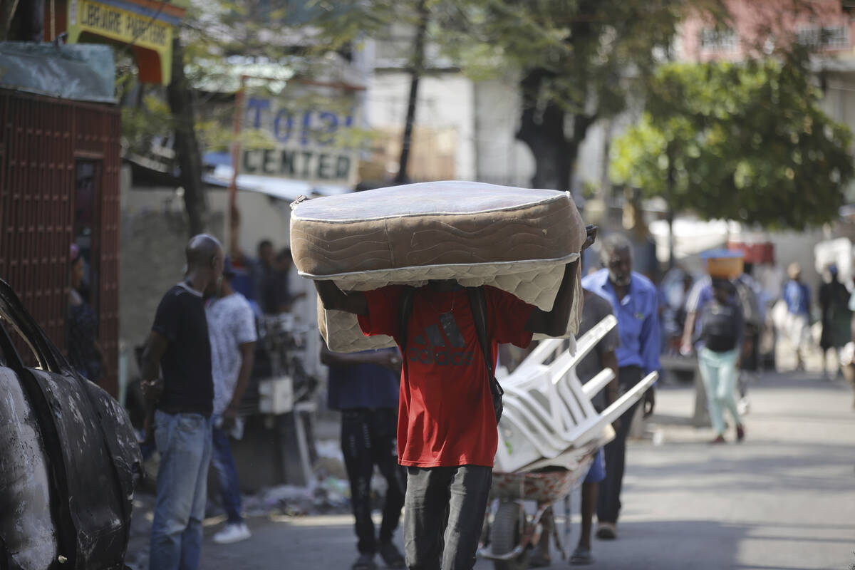 A man hauls a mattress as residents flee their homes due to gang violence in Port-au-Prince, Ha ...
