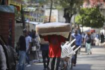 A man hauls a mattress as residents flee their homes due to gang violence in Port-au-Prince, Ha ...