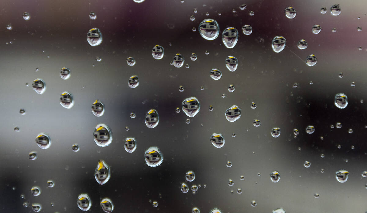 Raindrops reflect the Flamingo marquee as they bead up on glass atop a pedestrian bride crossin ...