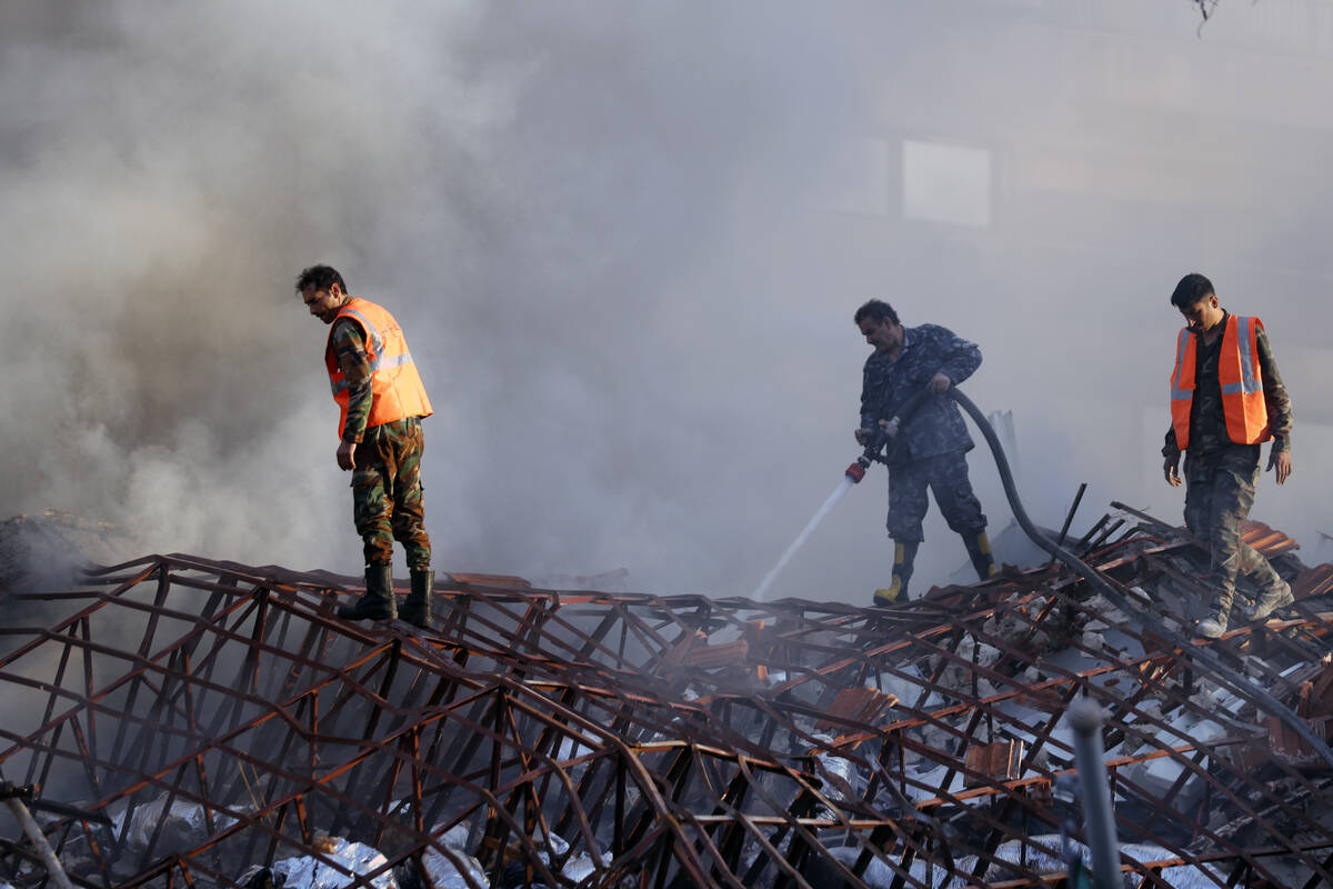 Emergency services work at a destroyed building hit by an air strike in Damascus, Syria, Monday ...