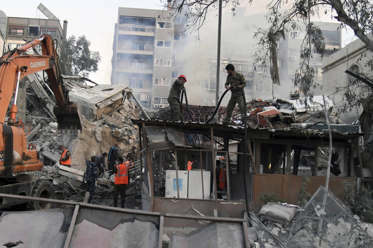 In this photo released by the official Syrian state news agency SANA, emergency service workers ...