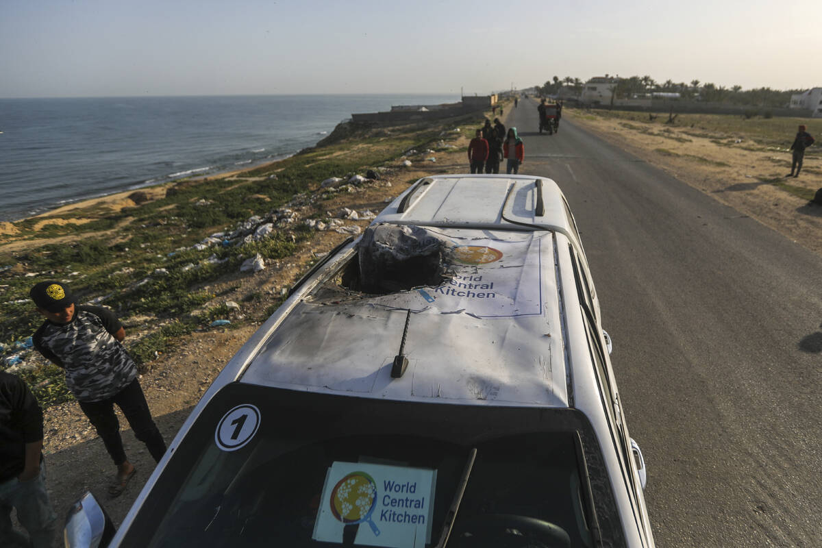 Palestinians inspect a vehicle with the logo of the World Central Kitchen wrecked by an Israeli ...