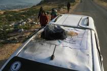 Palestinians inspect a vehicle with the logo of the World Central Kitchen wrecked by an Israeli ...