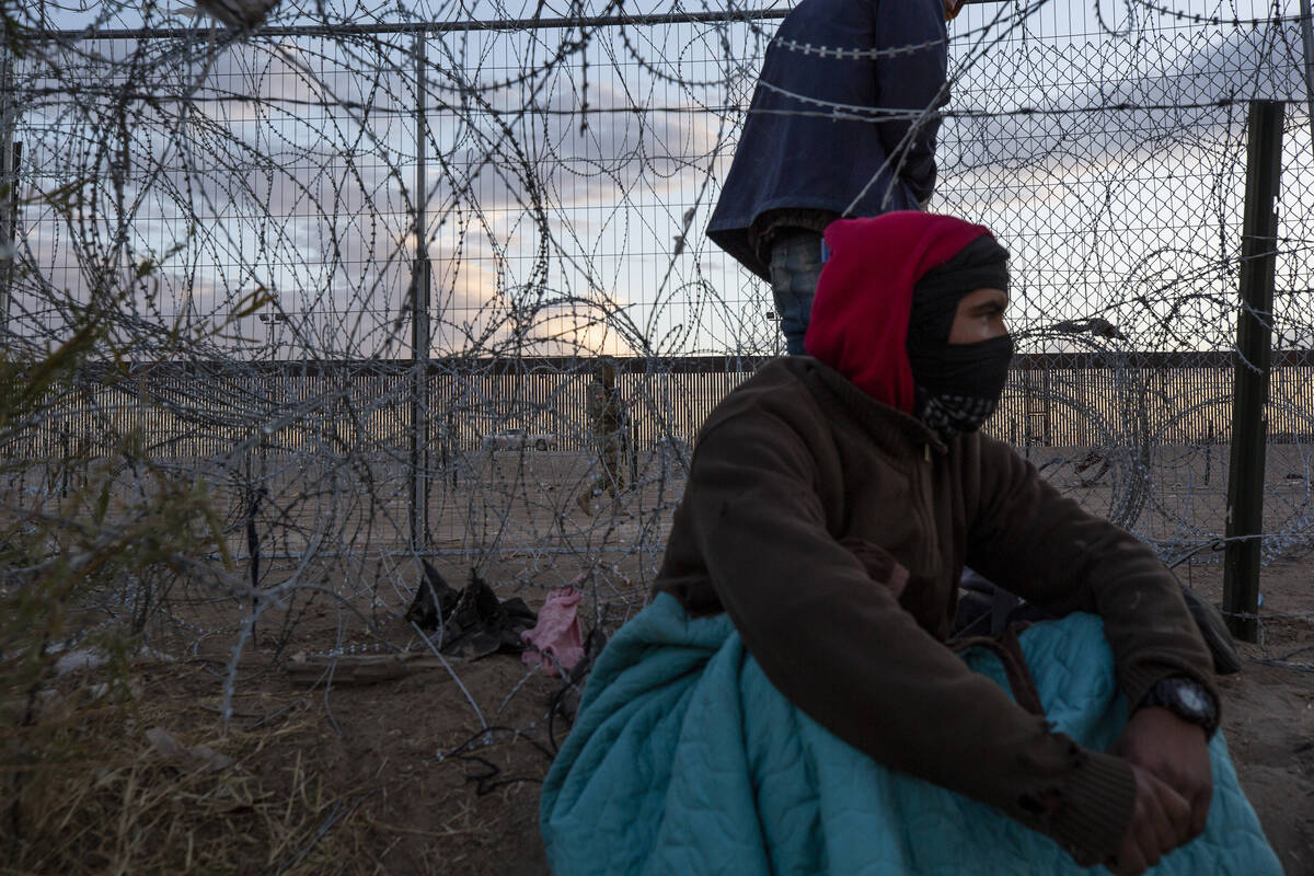 Migrant rest near a hole where a concertina barrier had been breached as a Texas National Guard ...