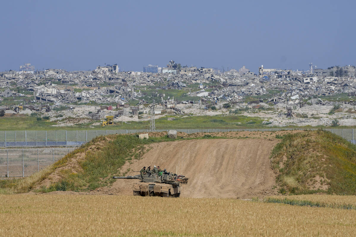 Israeli soldiers rest on top of their tank on the border with the Gaza Strip, in southern Israe ...