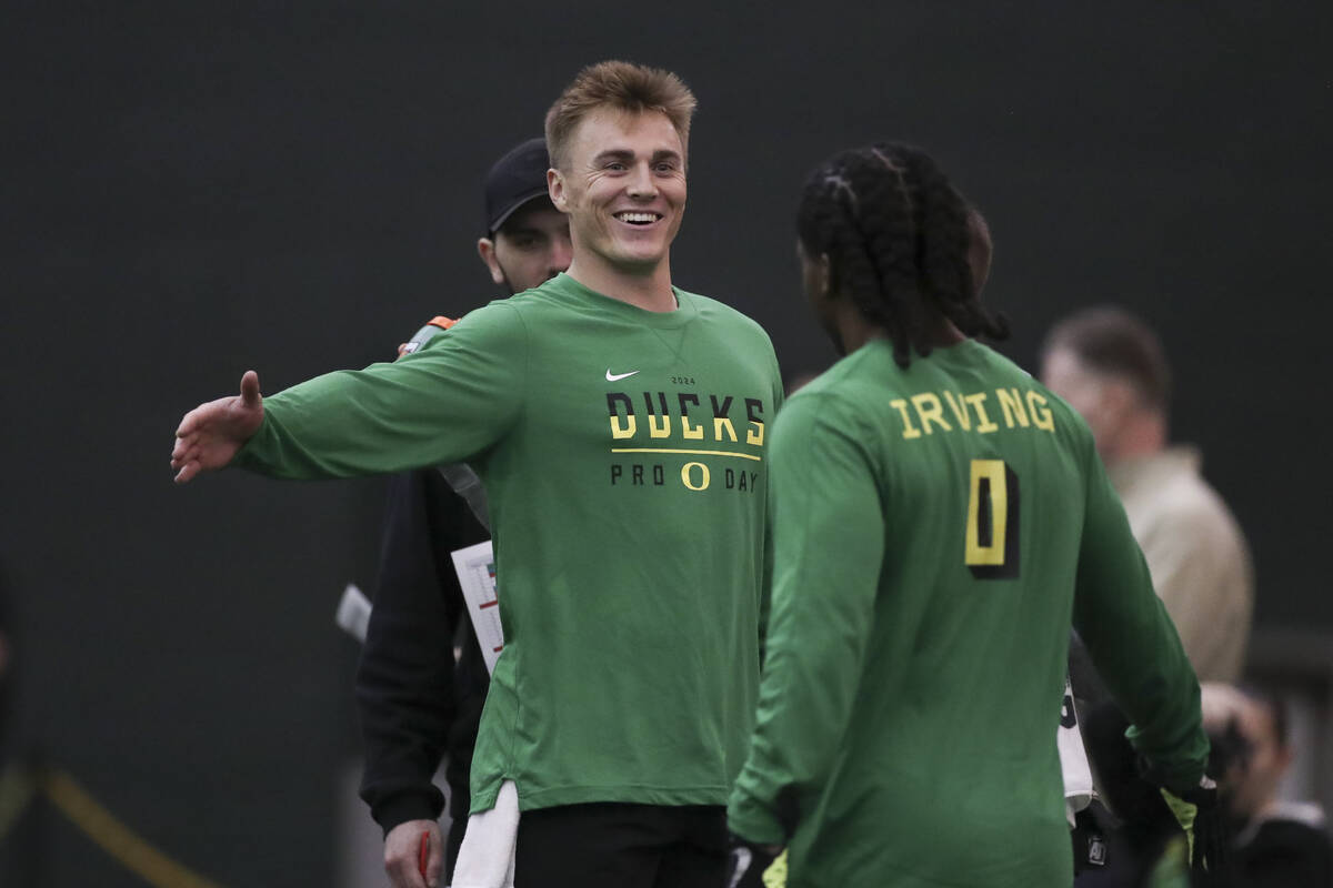 Oregon quarterback Bo Nix (10) high fives running back Bucky Irving (0) during a position drill ...