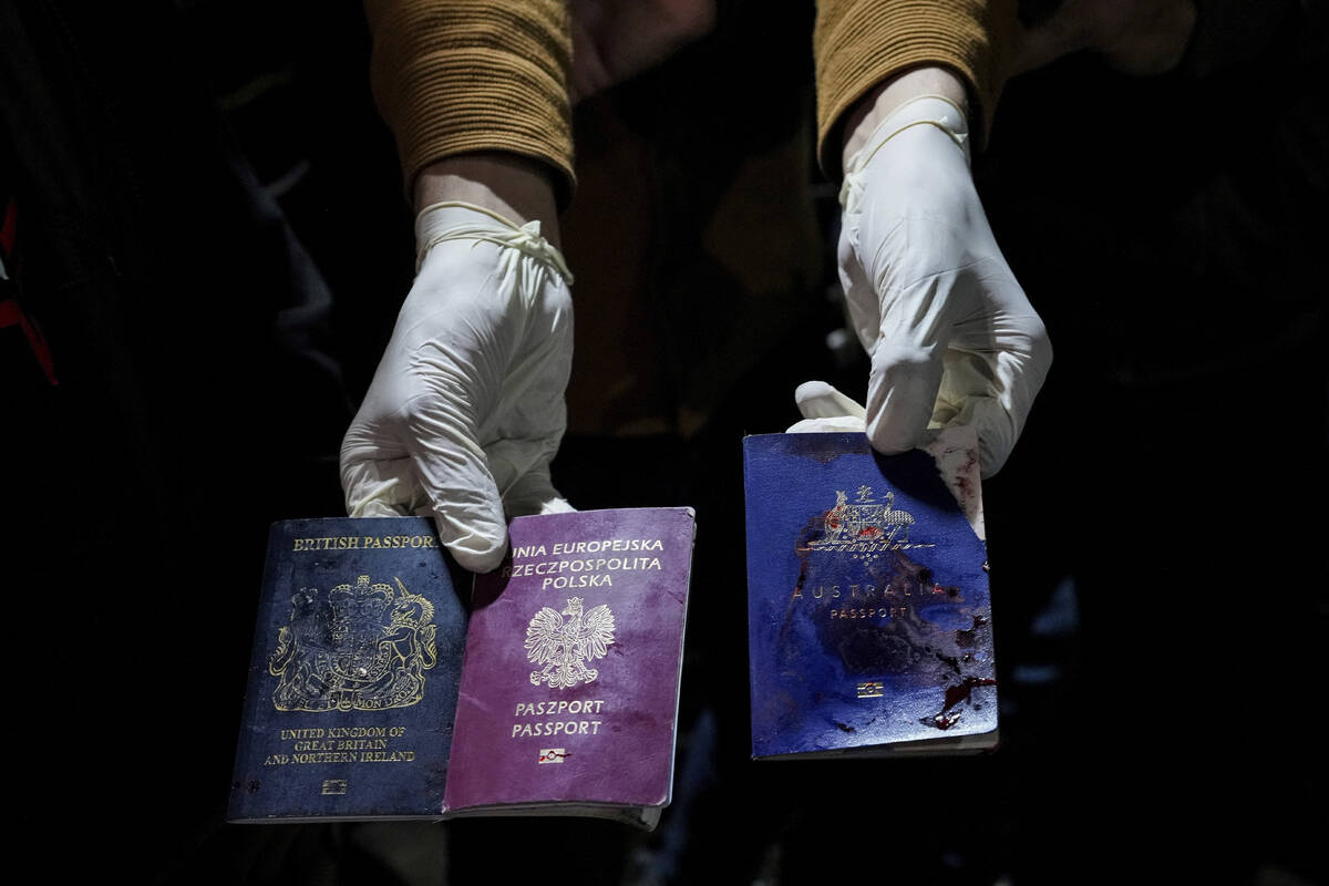 A man displays blood-stained British, Polish, and Australian passports after an Israeli airstri ...