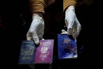 A man displays blood-stained British, Polish, and Australian passports after an Israeli airstri ...