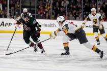 Arizona Coyotes center Logan Cooley (92) corrals the puck in front of Vegas Golden Knights defe ...