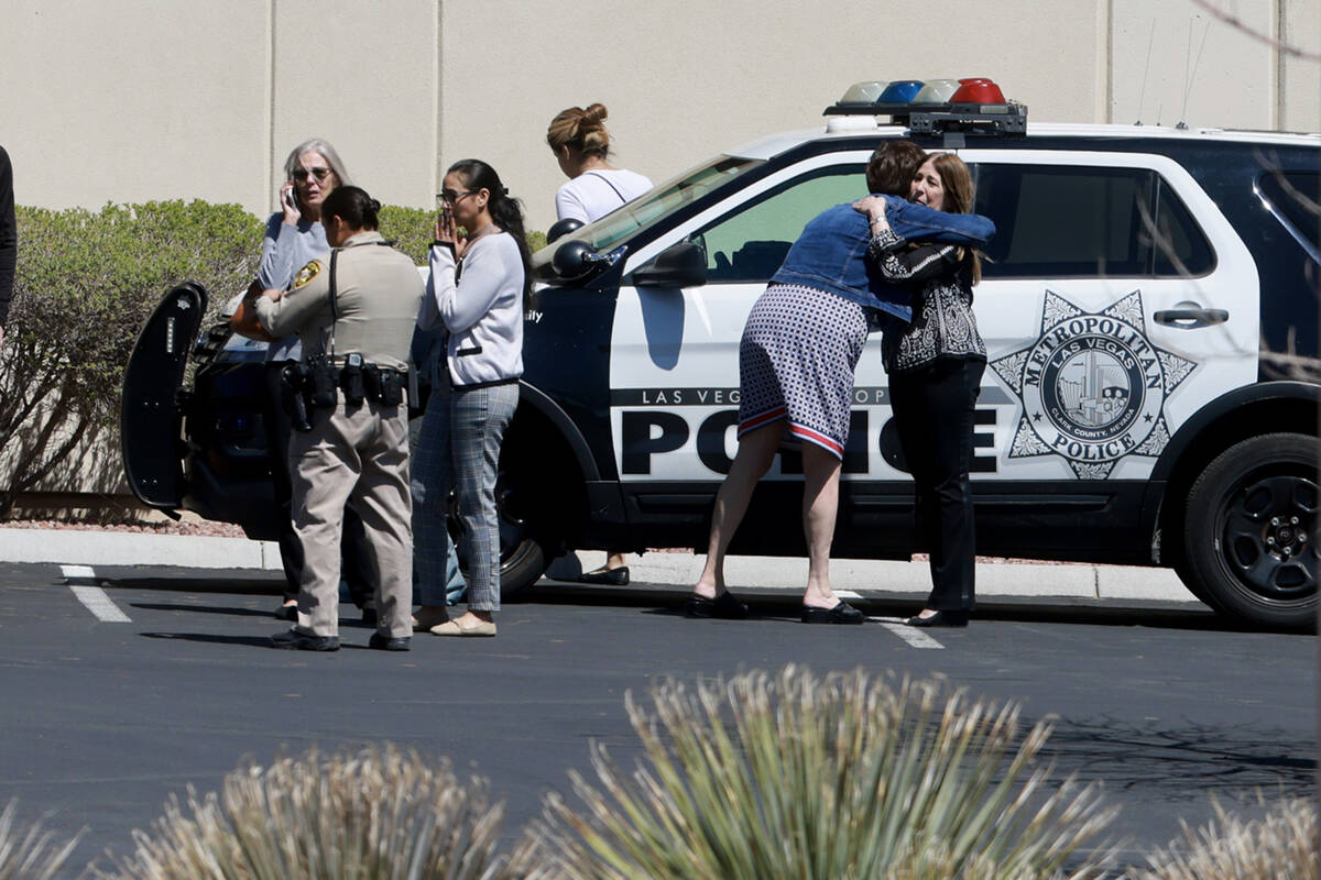 People hug as they wait with Las Vegas police investigating a shooting at City National Bank Bu ...