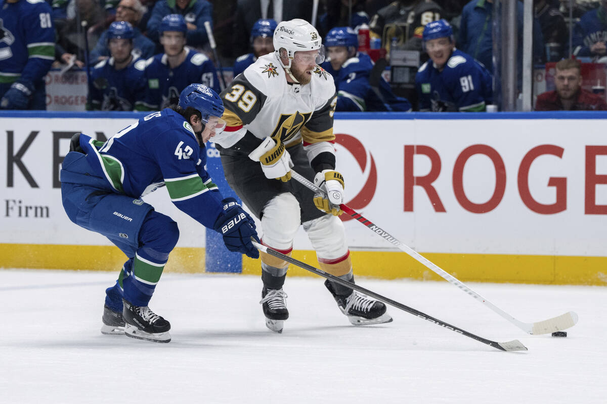 Vancouver Canucks' Quinn Hughes (43) and Vegas Golden Knights' Anthony Mantha (39) vie for the ...