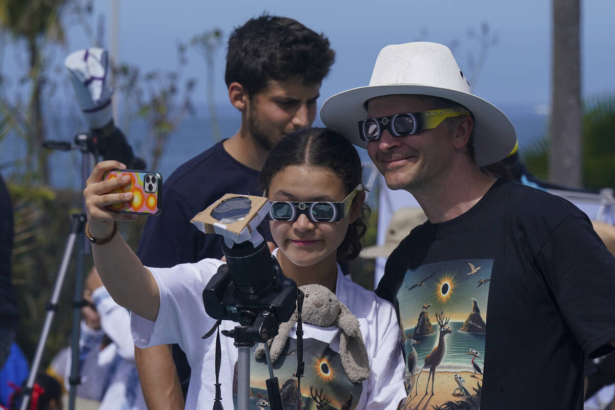 People take selfies as they watch and photograph a total solar eclipse in Mazatlan, Mexico, Mon ...