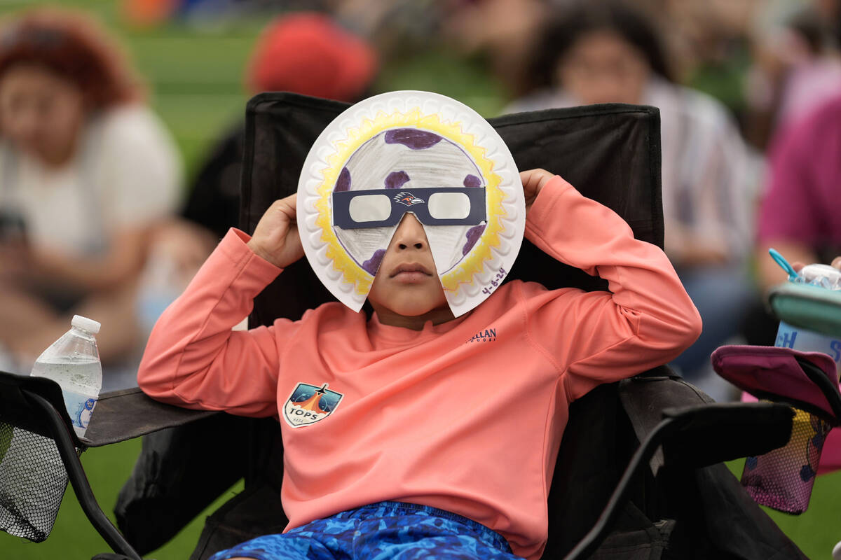 Yurem Rodriquez watches as the moon partially covers the sun during a total solar eclipse, as s ...