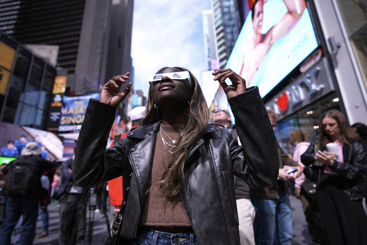 A woman views the solar eclipse in Times Square, Monday, April 8, 2024, in New York. (AP Photo/ ...