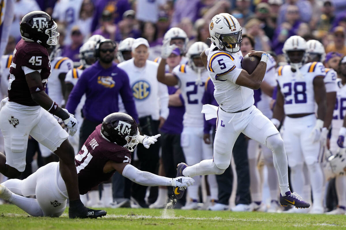 FILE - LSU quarterback Jayden Daniels (5) carries past Texas A&M linebacker Taurean York (2 ...