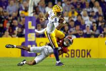 LSU quarterback Jayden Daniels (5) is tackled by Alabama defensive back Brian Branch, bottom, d ...