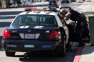A Los Angeles Police Department officer talks to an occupant inside of his squad car. (Getty Im ...