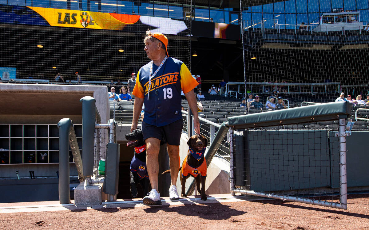 Fred Hassen, founder of Sit Means Sit dog training, walks onto the field with Aviators bat do ...