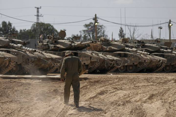 Israeli soldiers work on tanks at a staging ground near the border with the Gaza Strip, in sout ...