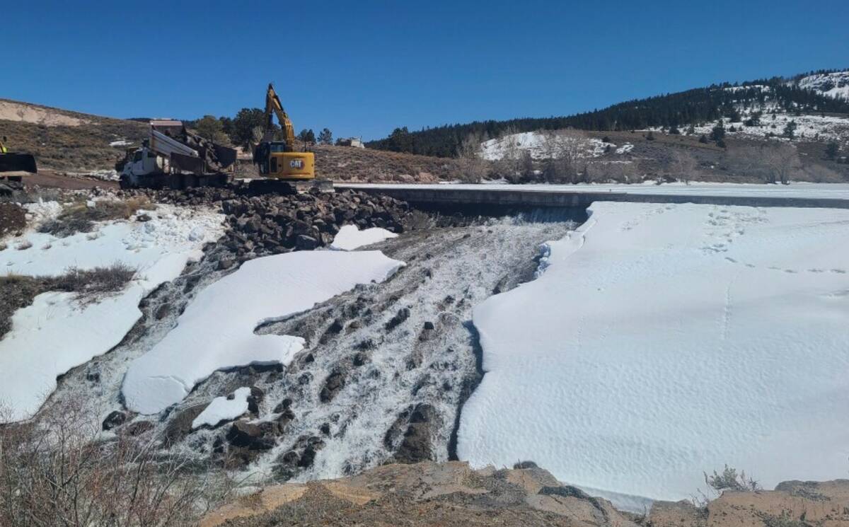 Crews use heavy machinery to place boulders downstream of the cracked Panguitch Lake Dam to rei ...