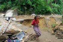 A survivor walks at an area affected by landslides in Battang Barat village, South Sulawesi, In ...