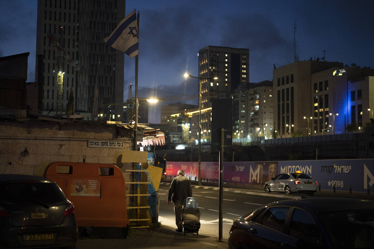 An elderly Jewish man pulls his cart on a street during the dusk in Jerusalem, Sunday, April 14 ...
