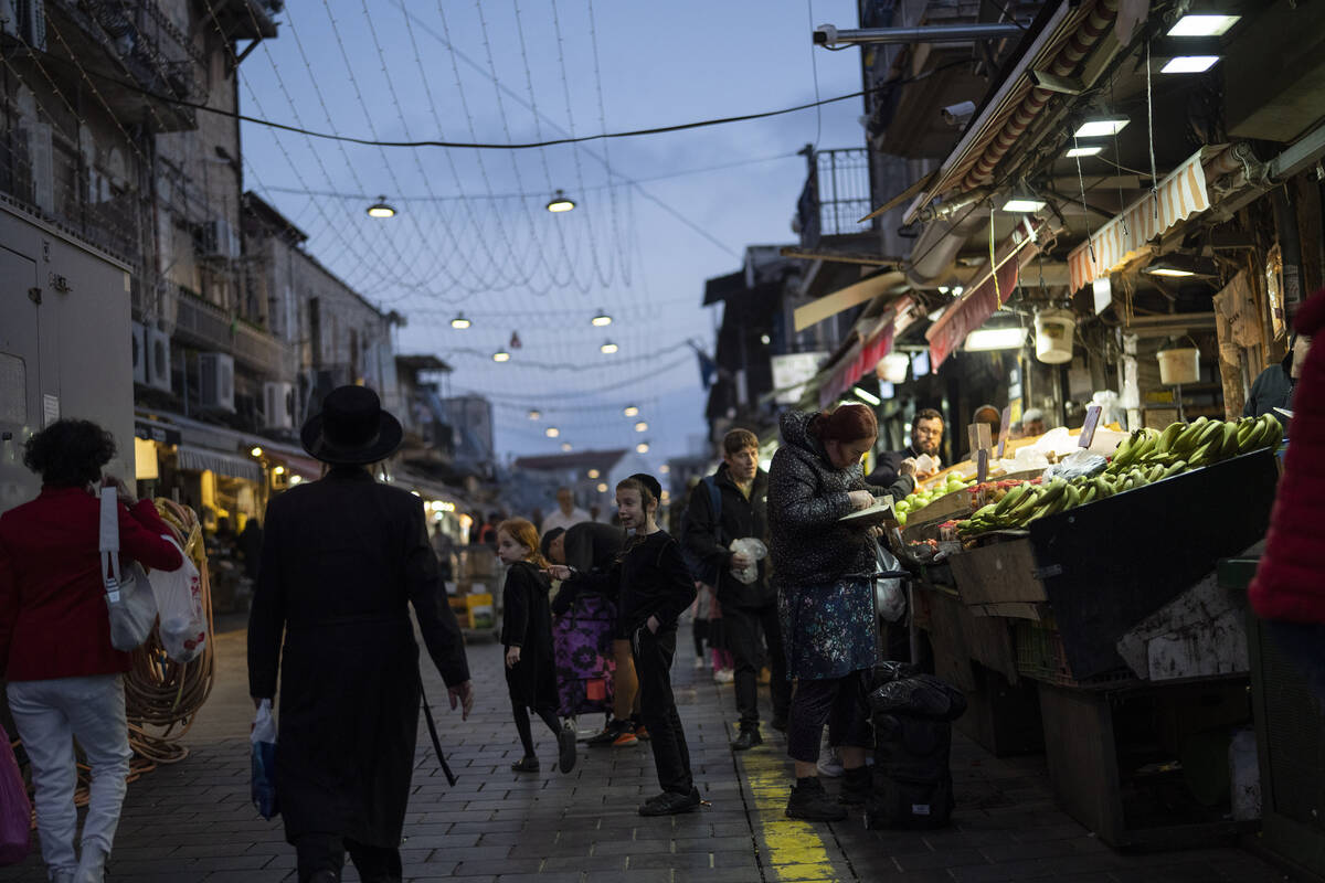 A woman buys fruits at a shop in the Mahane Yehuda market in Jerusalem, Sunday, April 14, 2024. ...