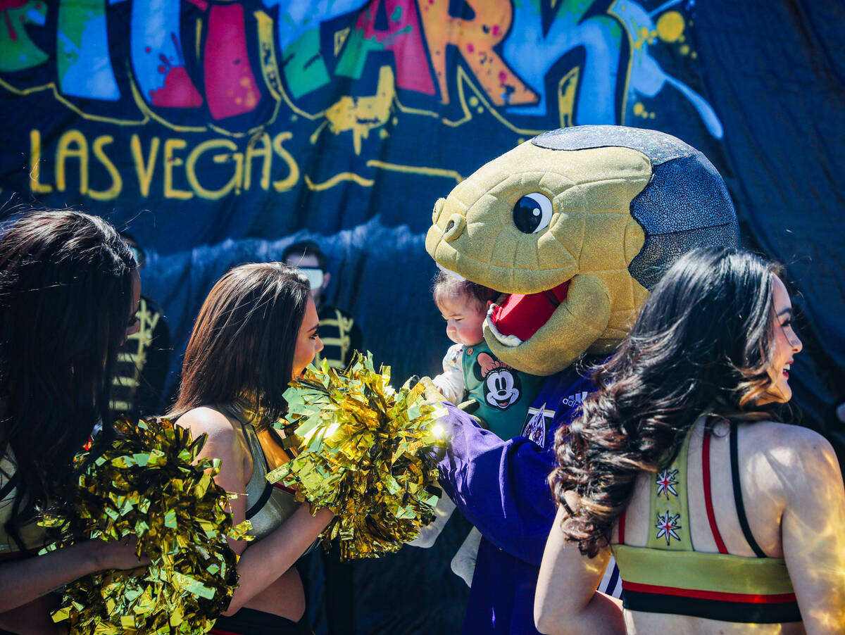 Golden Knights mascot Chance holds Jeydi Paez, 4 months, surrounded by Vegas Vivas at an event ...