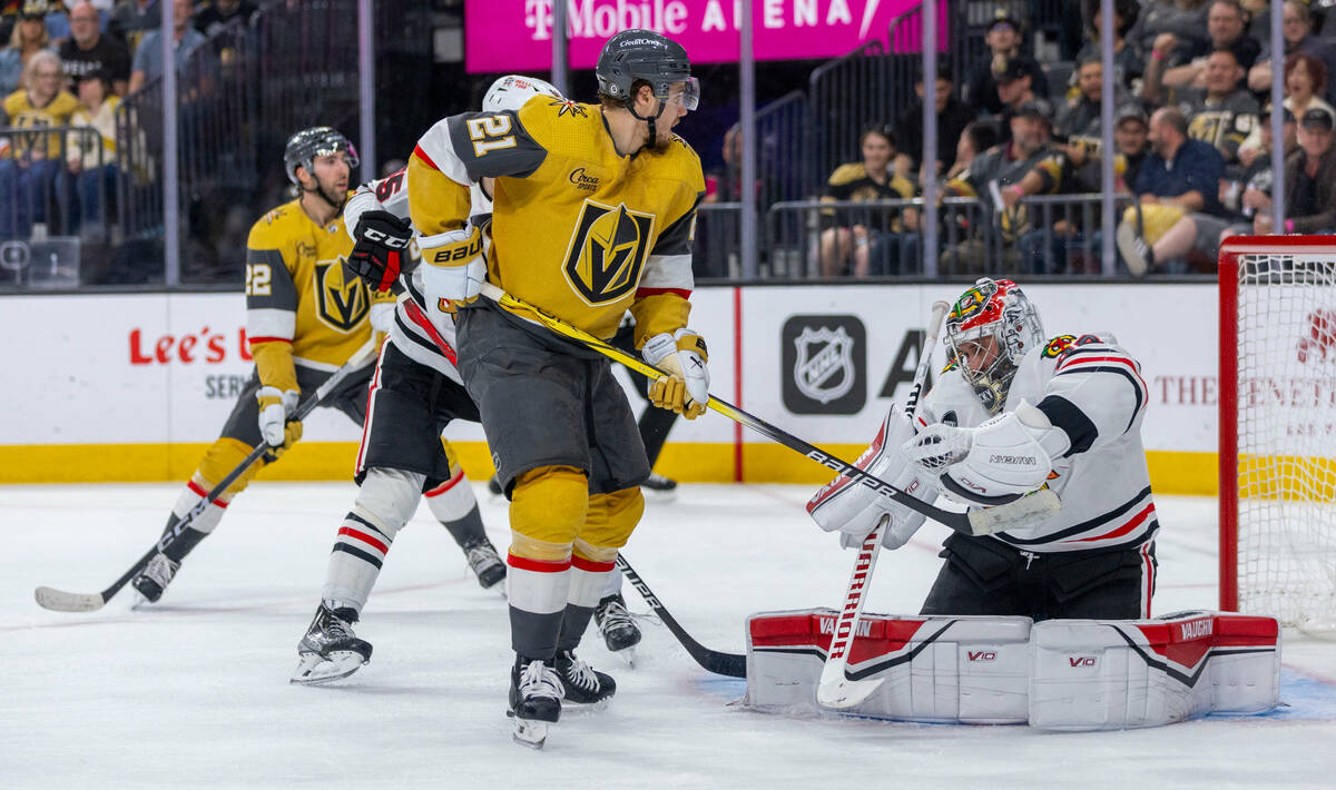 Golden Knights center Brett Howden (21) and Chicago Blackhawks goaltender Petr Mrazek (34) tang ...