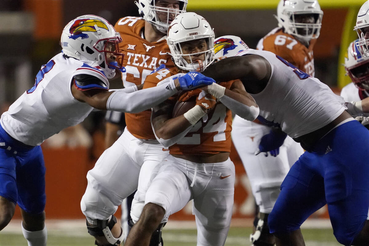 Texas running back Jonathon Brooks, center, is tackled by Kansas defensive lineman Caleb Sampso ...