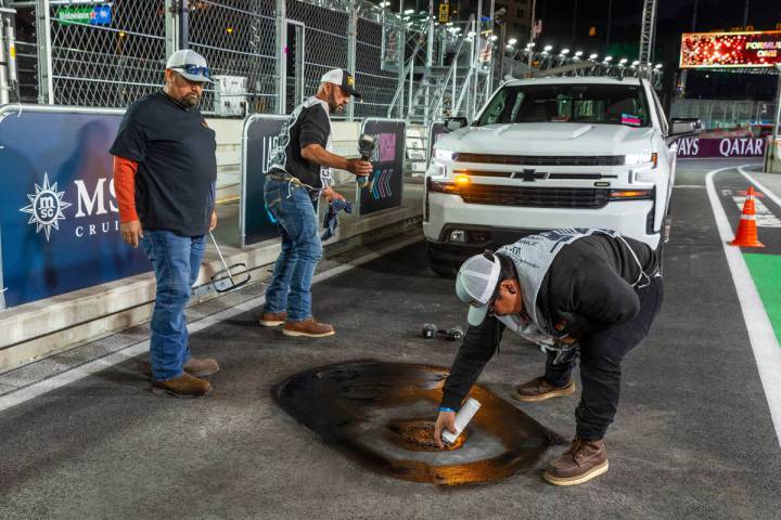 A crew from Las Vegas Paving ensures that a valve cover is secure and the pavement around it is ...