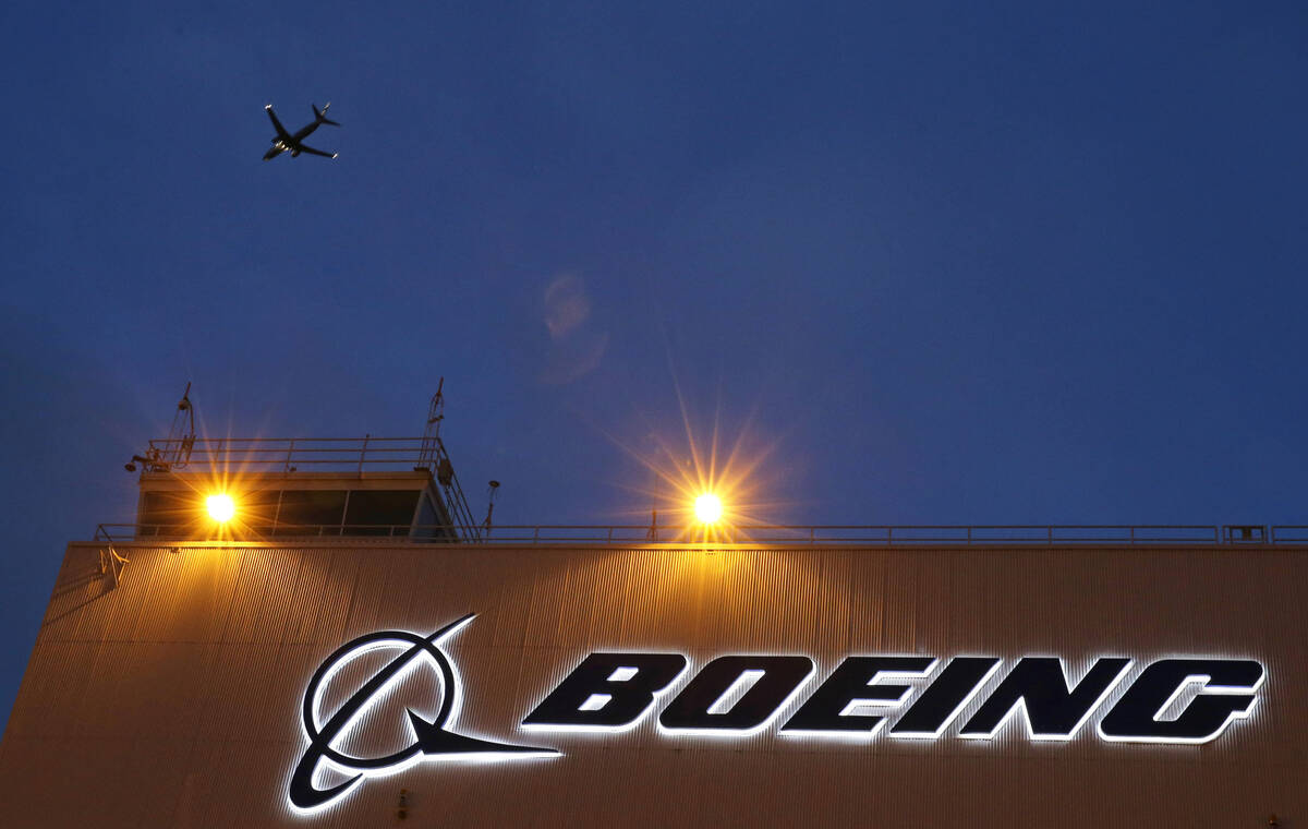 FILE - An airplane flies over a sign on Boeing's 737 delivery center, Oct. 19, 2015, at Boeing ...