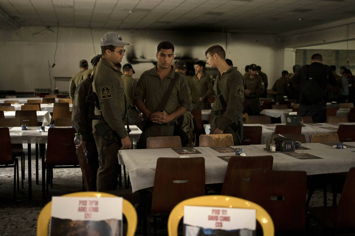Israeli soldiers look at chairs for hostages held in Gaza at a Passover Seder table on Thursday ...