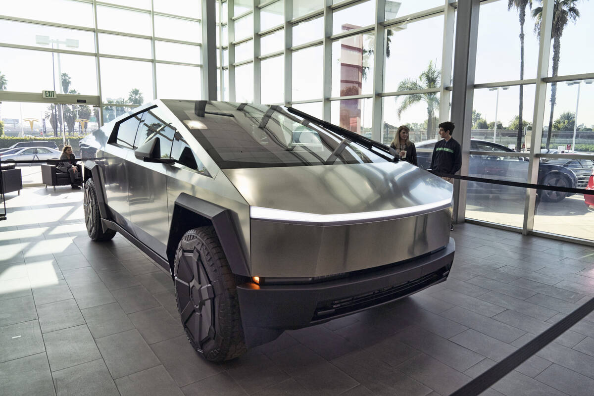 Tesla Cybertruck in showroom with people standing behind by windows.