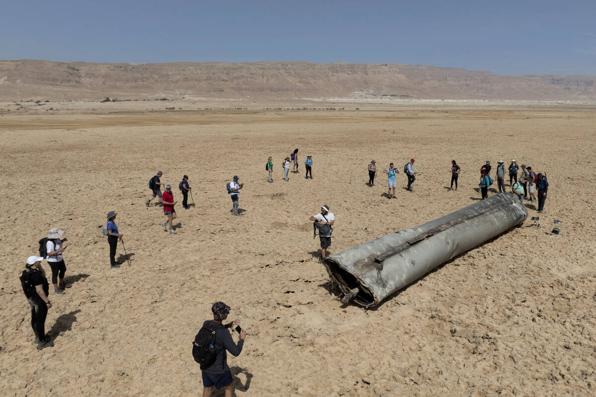 People gather around a component from an intercepted ballistic missile that fell near the Dead ...