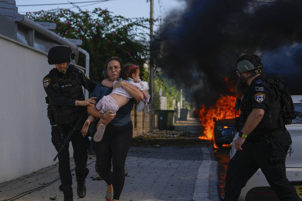 FILE - Police officers evacuate a woman and a child from a site hit by a rocket fired from the ...