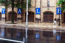 FILE - A woman walks by a Yale sign reflected in the rainwater on the Yale University campus, A ...