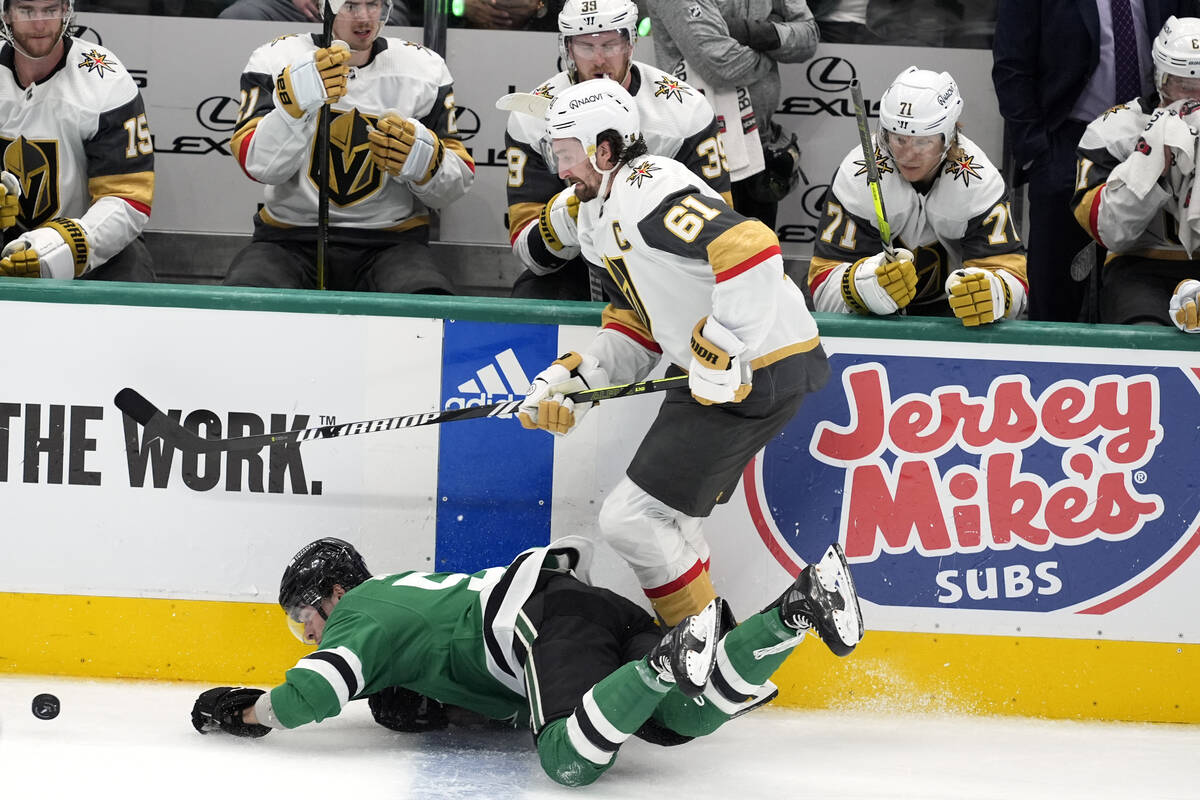 Dallas Stars center Wyatt Johnston, left, falls to the ice attempting to control the puck under ...