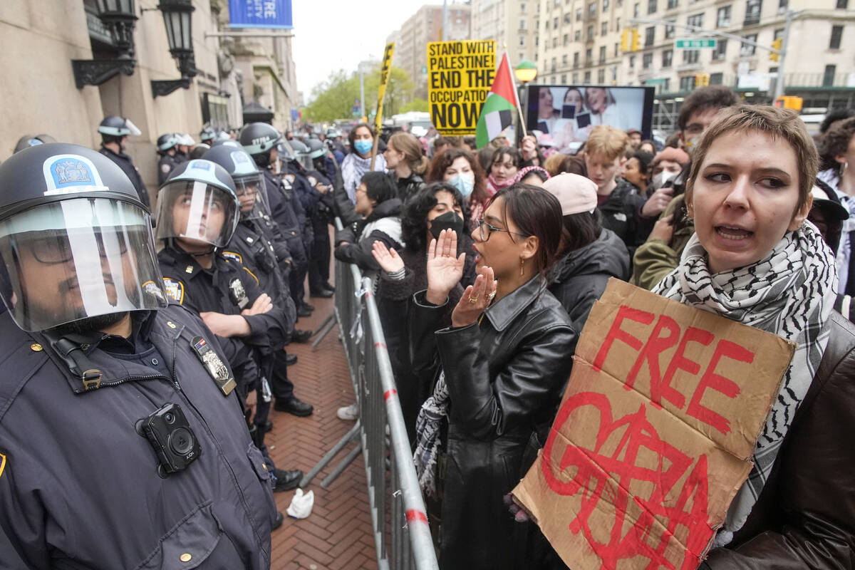FILE - Police in Riot gear stand guard as demonstrators chant slogans outside the Columbia Univ ...