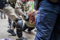 A demonstrator is restrained by police at a pro-Palestinian protest at the University of Texas, ...