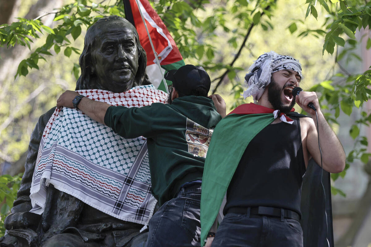 Qais Dana protests as a person puts a scarf on a Ben Franklin statue on Penn's campus during a ...